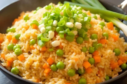 Fried rice with carrots, peas, and green onions in a bowl.