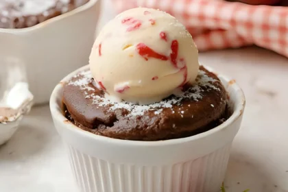 Chocolate lava cake topped with ice cream in white ramekin.