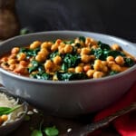 Bowl of smoky vegan chickpea and spinach stew with parsley on top