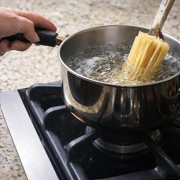 Adding Pasta to Boiling Water adding spaghetti into boiling water and stirring to prevent sticking