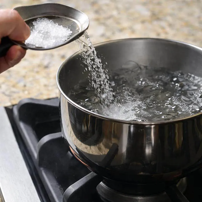 Salting Pasta Water adding salt to boiling water for pasta